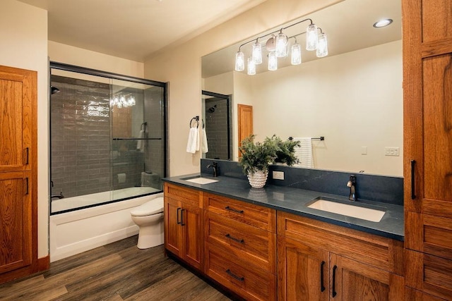 bathroom with double vanity, a sink, toilet, and wood finished floors