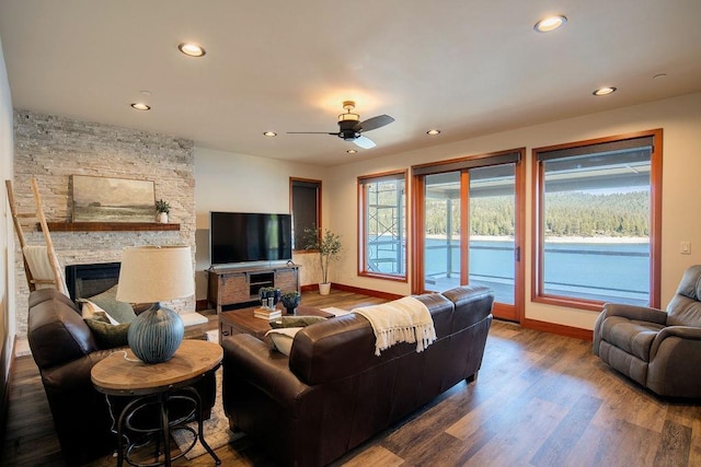 living room featuring recessed lighting, baseboards, wood finished floors, and a stone fireplace