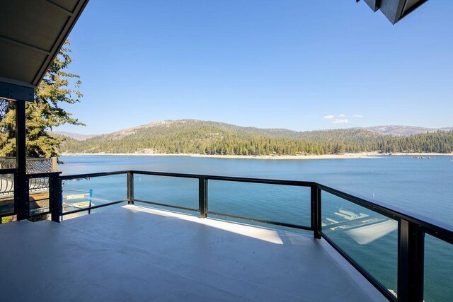 exterior space featuring a balcony, a view of trees, and a water and mountain view