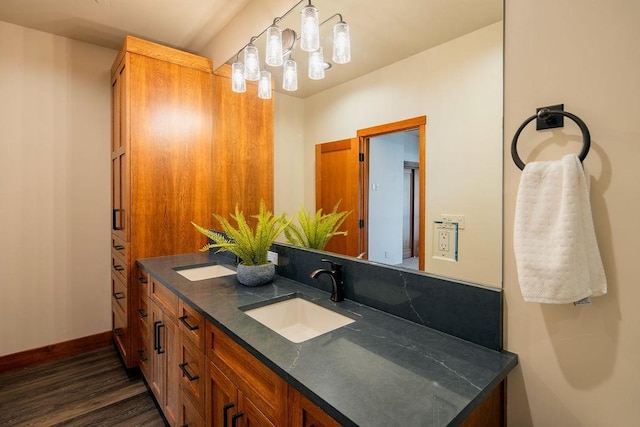 full bathroom featuring double vanity, wood finished floors, a sink, and baseboards