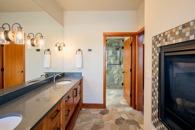 bathroom featuring a sink, a shower stall, baseboards, and double vanity