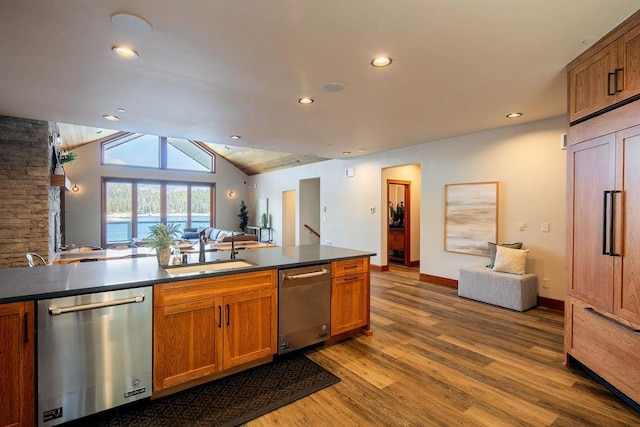 kitchen featuring a sink, dark countertops, open floor plan, and stainless steel dishwasher