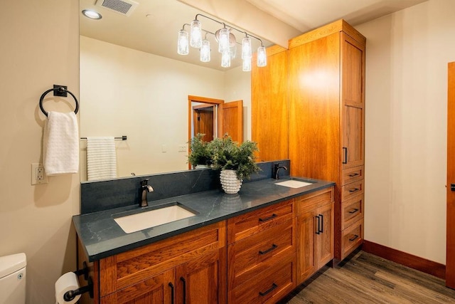 bathroom featuring toilet, visible vents, a sink, and wood finished floors