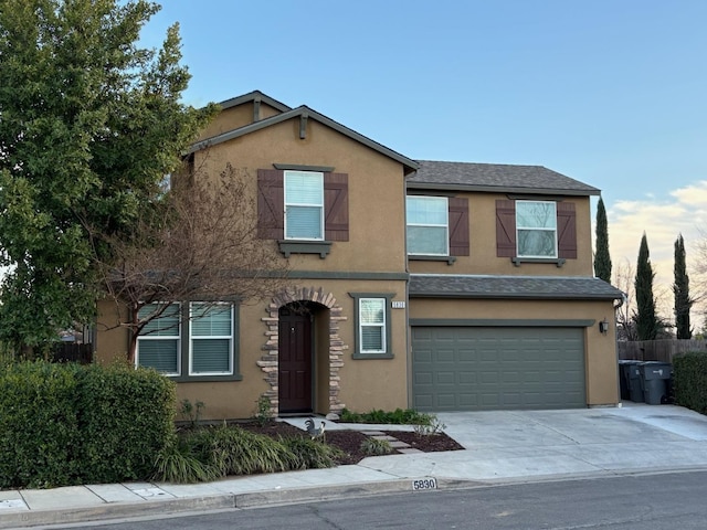 traditional home with concrete driveway, fence, an attached garage, and stucco siding