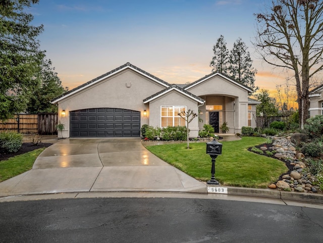 view of front of home featuring a front yard, fence, stucco siding, concrete driveway, and a garage