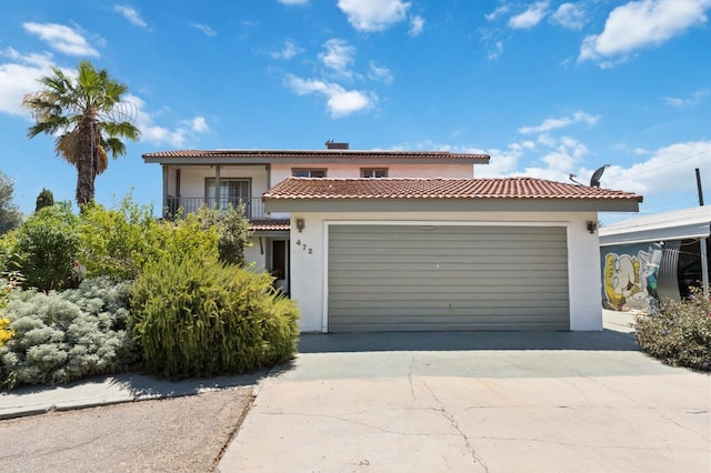 mediterranean / spanish-style home featuring an attached garage, a balcony, driveway, and stucco siding