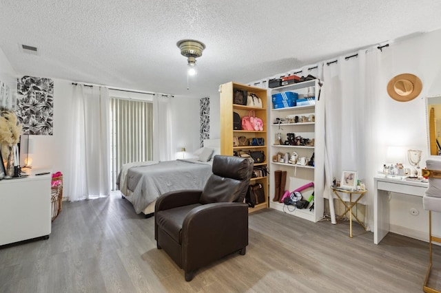 bedroom featuring light wood-style floors, visible vents, and a textured ceiling