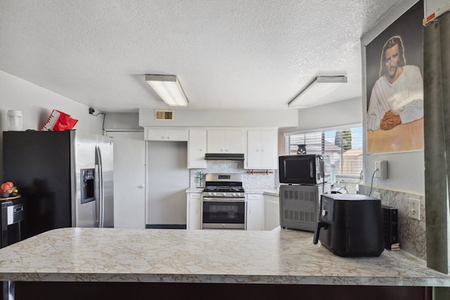 kitchen with visible vents, white cabinets, decorative backsplash, stainless steel appliances, and under cabinet range hood