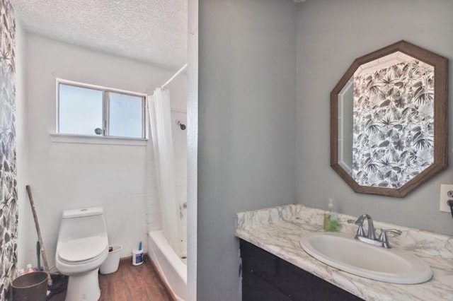 full bathroom with a textured ceiling, toilet, wood finished floors, vanity, and shower / bath combo with shower curtain