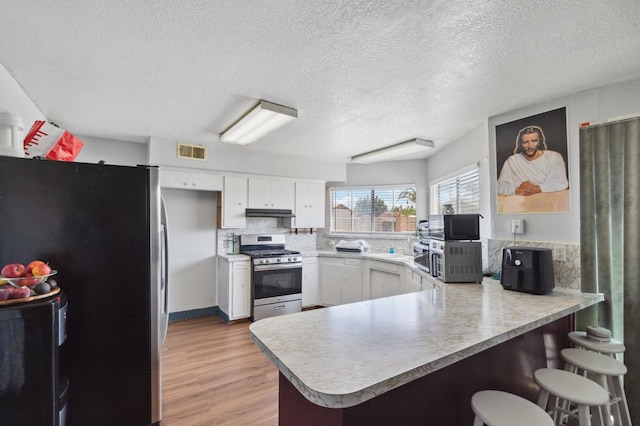 kitchen with light countertops, visible vents, appliances with stainless steel finishes, light wood-type flooring, and a peninsula