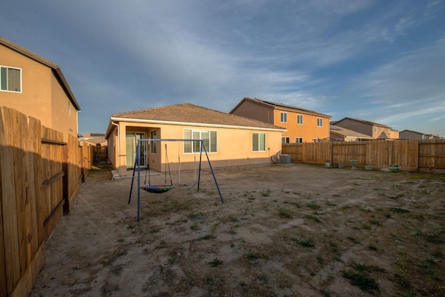 back of property with central AC unit, a fenced backyard, and stucco siding