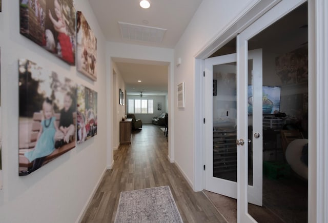 corridor with visible vents, baseboards, and wood finished floors