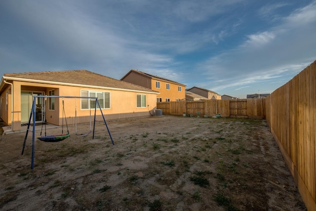 back of property with a fenced backyard, central AC unit, and stucco siding