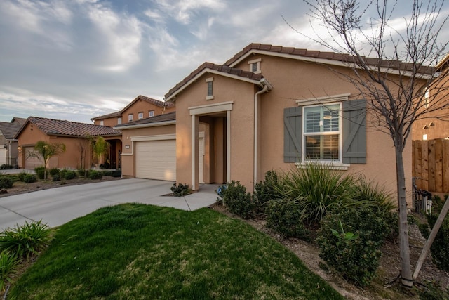 mediterranean / spanish house with stucco siding, a front yard, fence, a garage, and driveway