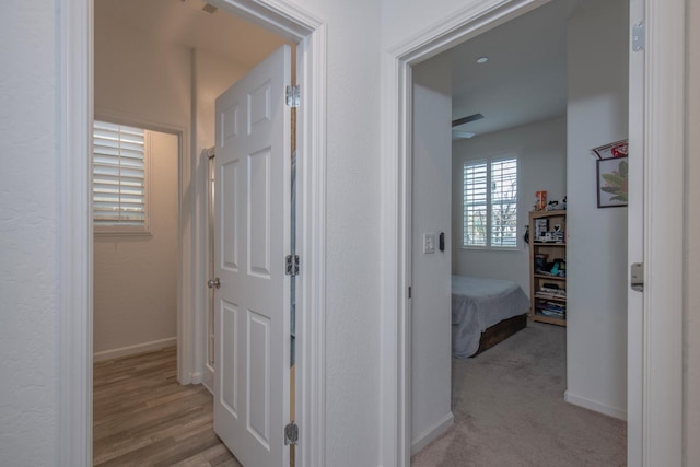 hall with light colored carpet and baseboards