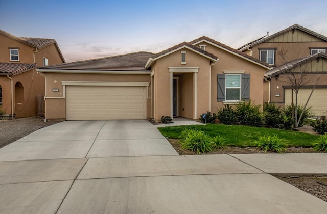 view of front of house with driveway, an attached garage, a tile roof, and stucco siding