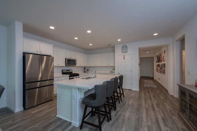 kitchen featuring appliances with stainless steel finishes, dark wood finished floors, white cabinetry, and a sink