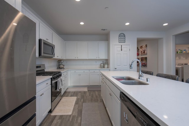 kitchen featuring stainless steel appliances, a sink, light countertops, and washer and dryer