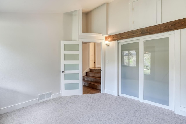 unfurnished room featuring baseboards, visible vents, stairway, and carpet flooring