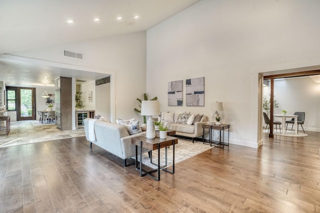 living room featuring recessed lighting, visible vents, high vaulted ceiling, light wood-type flooring, and baseboards