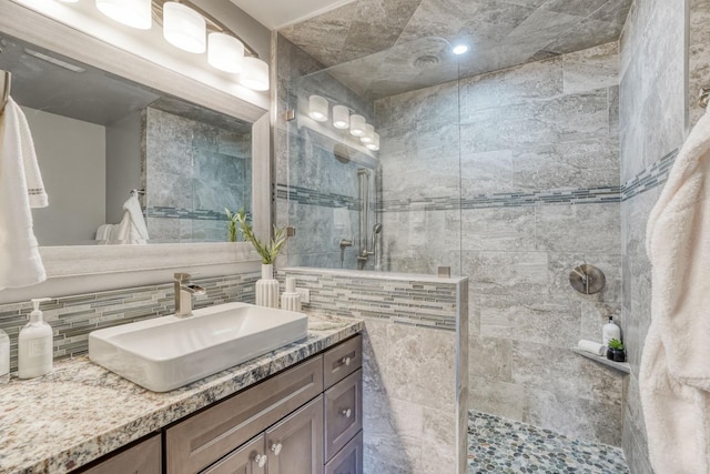 bathroom featuring backsplash, vanity, and a walk in shower