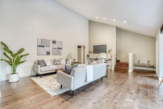 living area featuring high vaulted ceiling, recessed lighting, wood finished floors, baseboards, and stairway