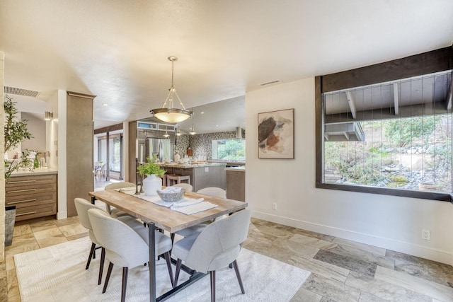 dining space featuring stone finish floor, visible vents, and baseboards