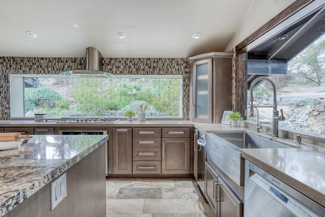 kitchen featuring recessed lighting, stainless steel appliances, wall chimney range hood, decorative backsplash, and light stone countertops