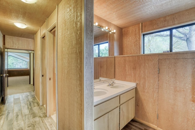 full bath featuring double vanity, a textured ceiling, a sink, and wood finished floors