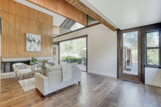 living room with a towering ceiling, a fireplace, baseboards, and wood finished floors