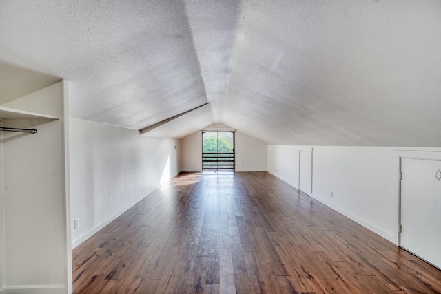 bonus room with lofted ceiling, a textured ceiling, baseboards, and hardwood / wood-style floors