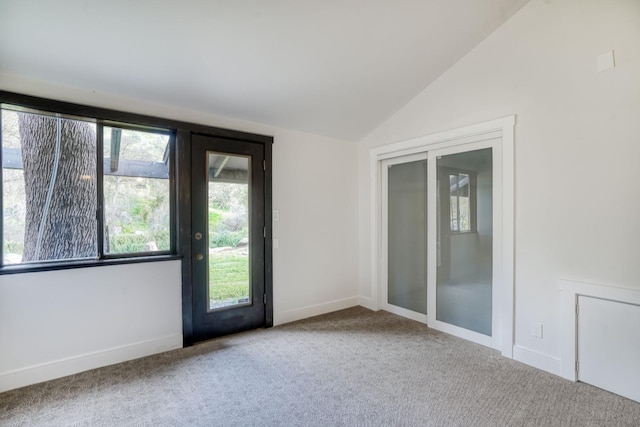 spare room featuring lofted ceiling, carpet, and baseboards