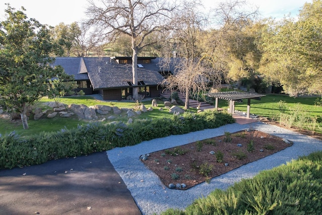 view of property's community featuring a lawn and a pergola