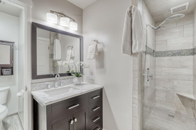 full bathroom featuring visible vents, a shower stall, toilet, and vanity