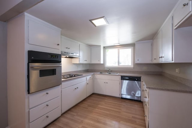 kitchen with appliances with stainless steel finishes, white cabinetry, a sink, light wood-type flooring, and under cabinet range hood