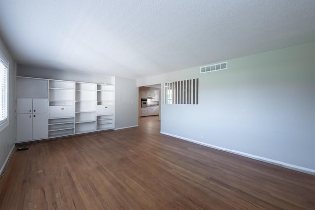 unfurnished living room featuring baseboards, a textured ceiling, visible vents, and dark wood-style flooring