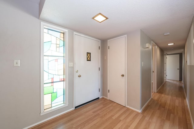 entrance foyer with light wood-type flooring, baseboards, and a textured ceiling