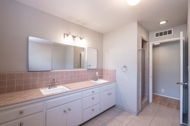 bathroom with visible vents, a sink, decorative backsplash, and double vanity