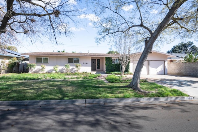 ranch-style house featuring a garage, a front yard, driveway, and fence