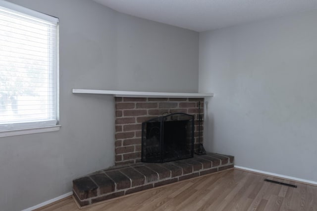 room details with a fireplace, wood finished floors, visible vents, and baseboards