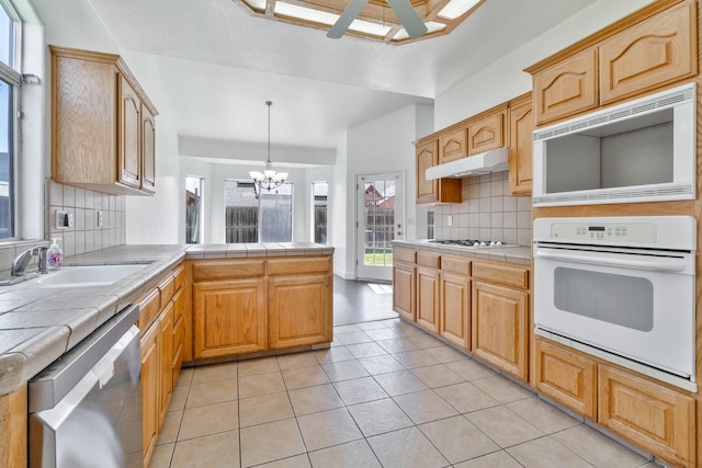 15877 W C St, Kerman, CA 93630 - kitchen featuring white appliances, tile counters, tasteful backsplash, a chandelier, and a peninsula