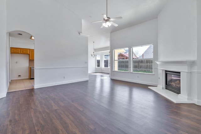 15877 W C St, Kerman, CA 93630 - unfurnished living room with a ceiling fan, a high ceiling, a glass covered fireplace, wood finished floors, and arched walkways