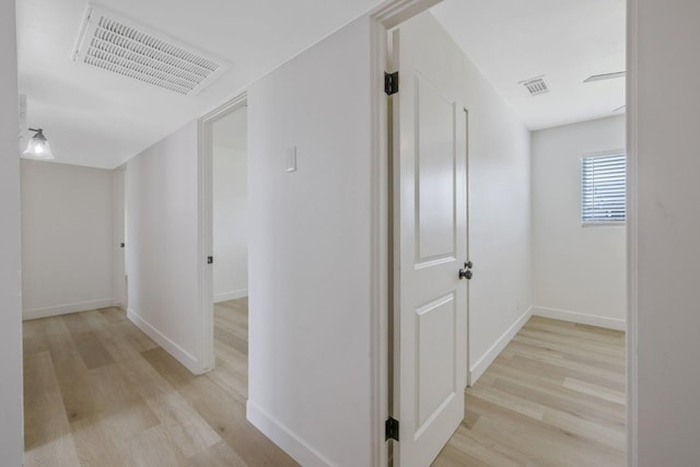 corridor with visible vents, light wood-style flooring, and baseboards