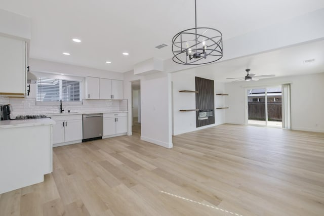 kitchen featuring light countertops, decorative backsplash, stainless steel dishwasher, white cabinetry, and a sink