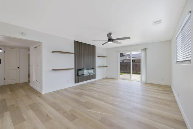 unfurnished living room with a fireplace, visible vents, a ceiling fan, baseboards, and light wood finished floors