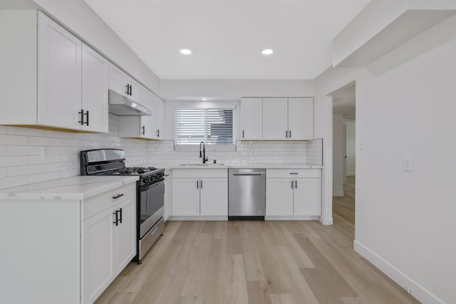 kitchen featuring stainless steel appliances, a sink, white cabinets, and under cabinet range hood