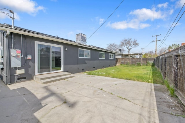 back of house featuring entry steps, a fenced backyard, crawl space, a yard, and stucco siding