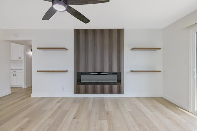 unfurnished living room featuring light wood finished floors, ceiling fan, baseboards, and a glass covered fireplace