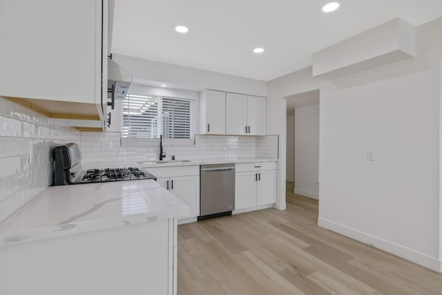 kitchen featuring range with gas stovetop, decorative backsplash, stainless steel dishwasher, white cabinetry, and a sink