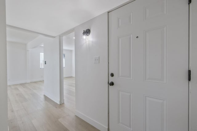 interior space featuring baseboards and light wood finished floors